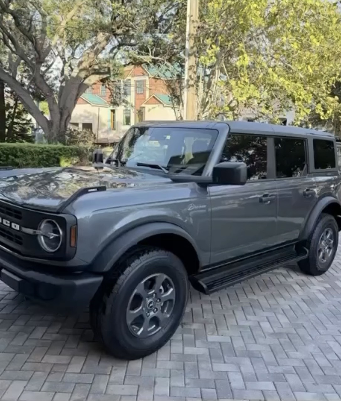 A freshly detailed gray Ford Bronco with a glossy finish parked on a brick driveway